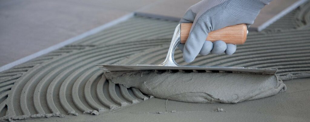 Nanášení lepidla zubovou stěrkou pro lepší přilnavost.