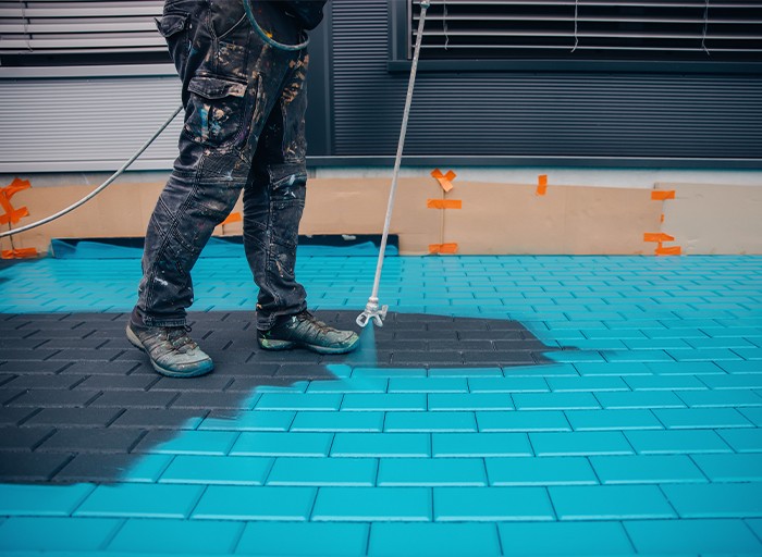 Aplikace základní vrstvy nátěru na chodník pomocí technologie airless.